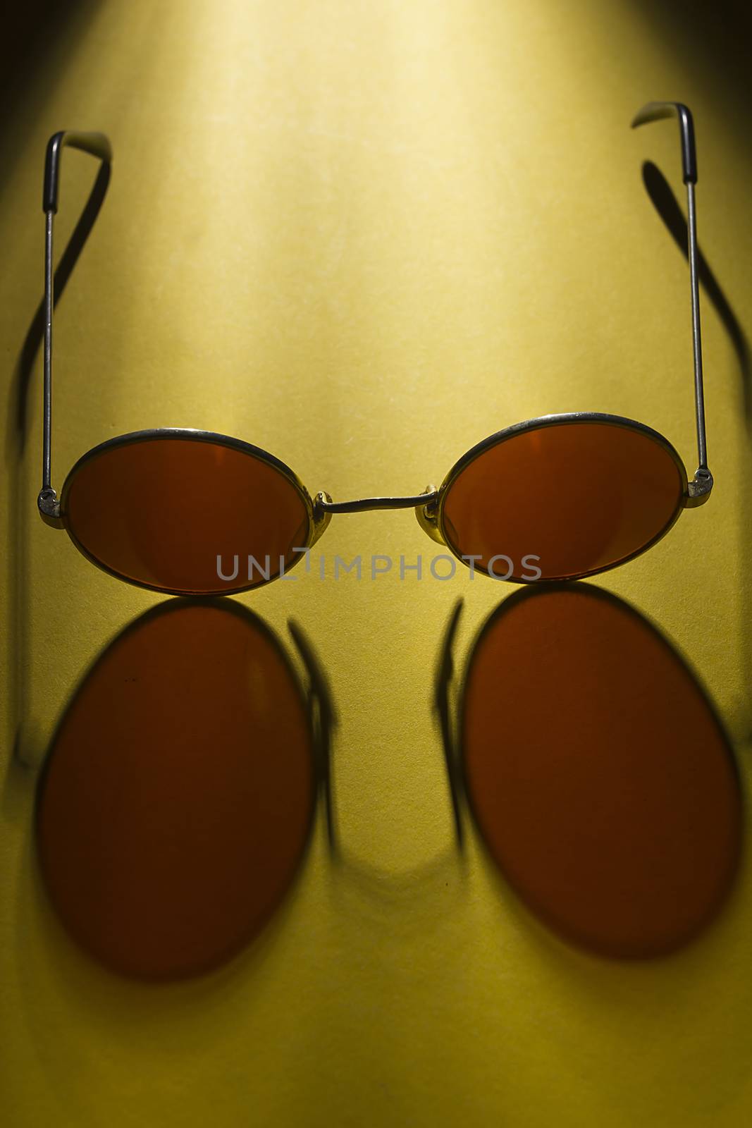 Round sunglasses on the table with yellow coating