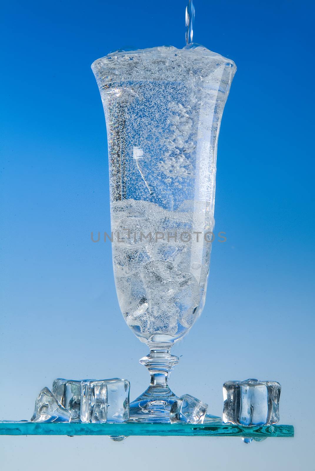 Glass and pouring water on a blue backround