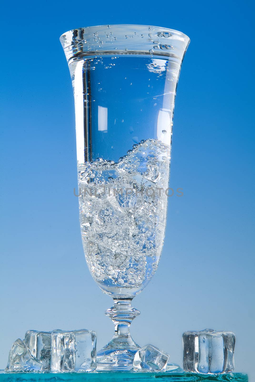 Glass and pouring water on a blue backround