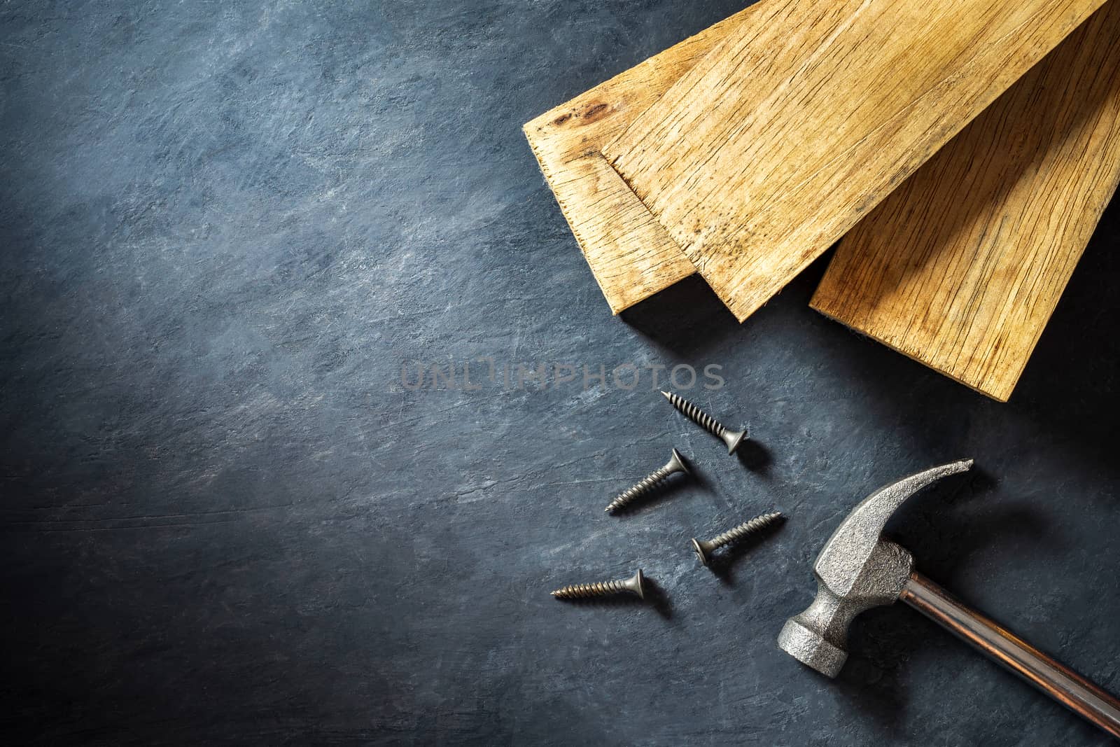 Hammer and lumber on black cement background. Top view and copy space for text. Concept of carpenter or construct.