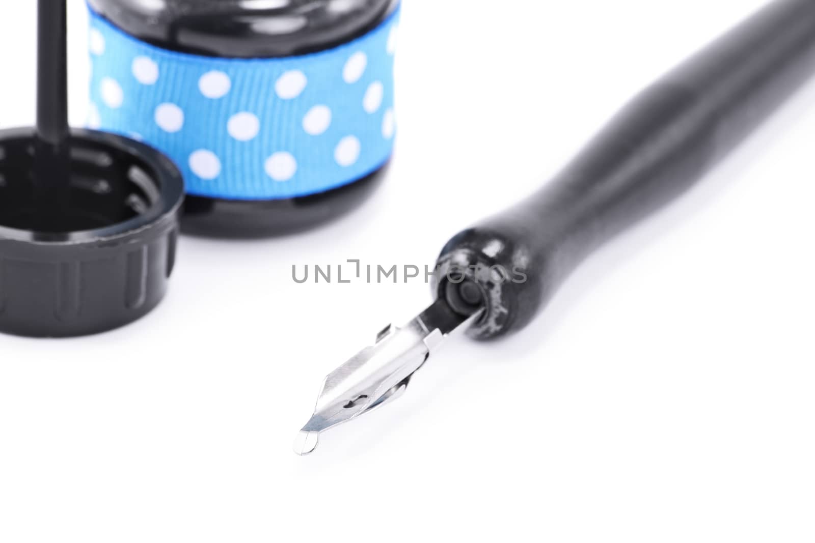 Close up shot of a dip pen and ink bottle, isolated on white background.