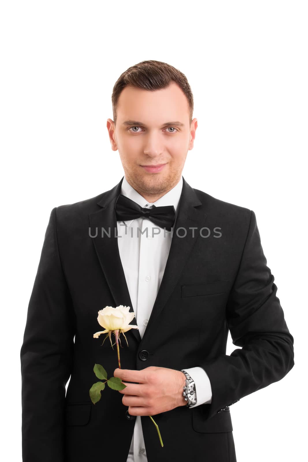 A portrait of a smiling handsome young man in a suit holding a flower, isolated on white background.
