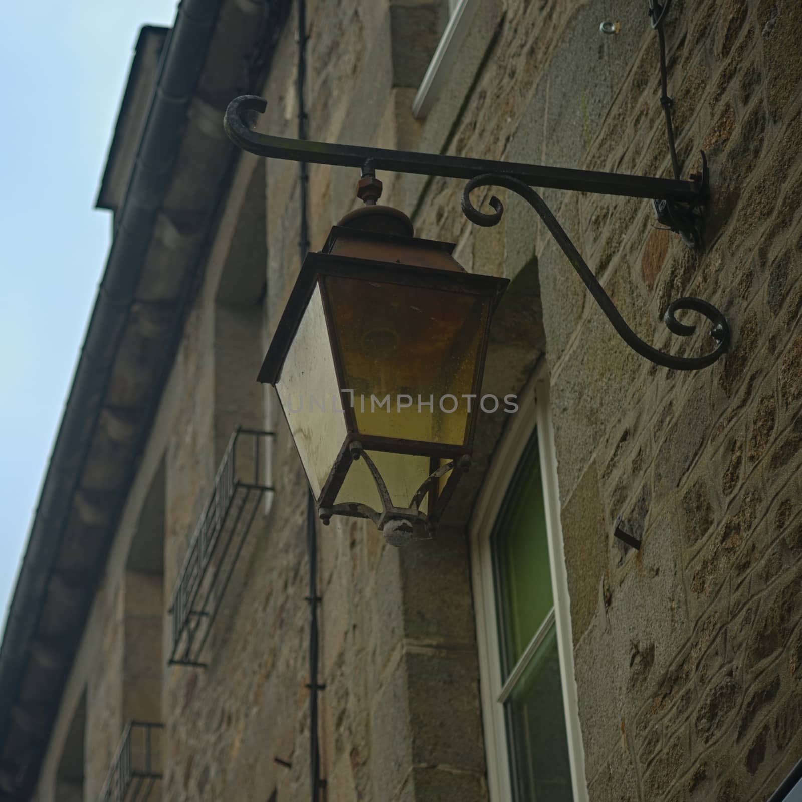 View from bellow on lantern on stone wall with windows by sheriffkule