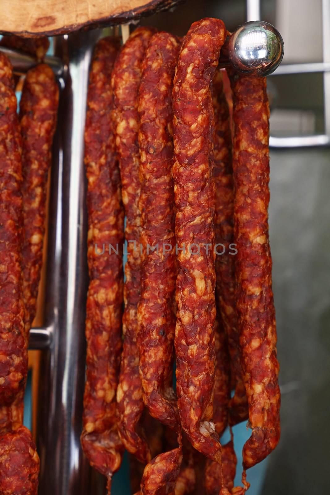 Cured smoked red meat sausages hanging in store by BreakingTheWalls