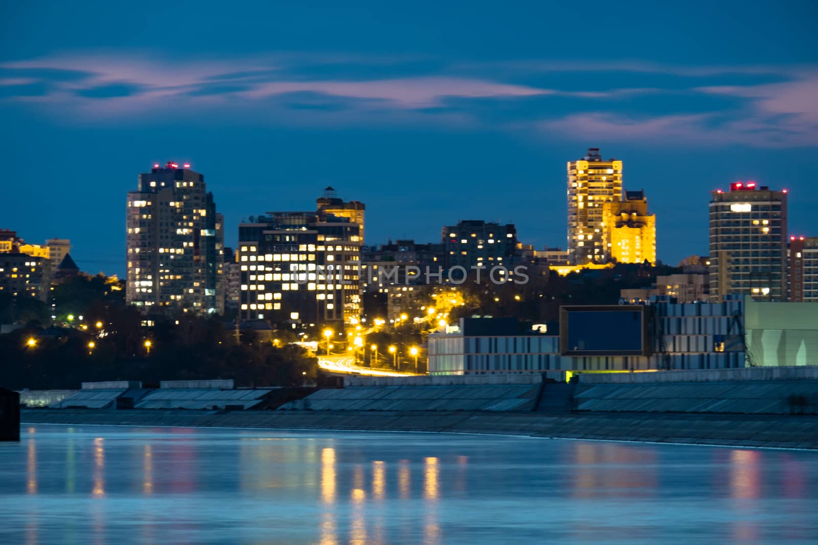 Night View of the city of Khabarovsk from the Amur river. Blue night sky. The night city is brightly lit with lanterns.