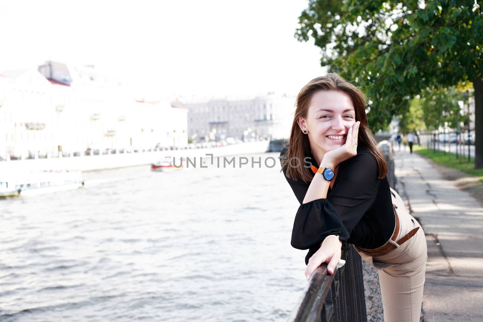 Beautiful young woman on embankment near river in city