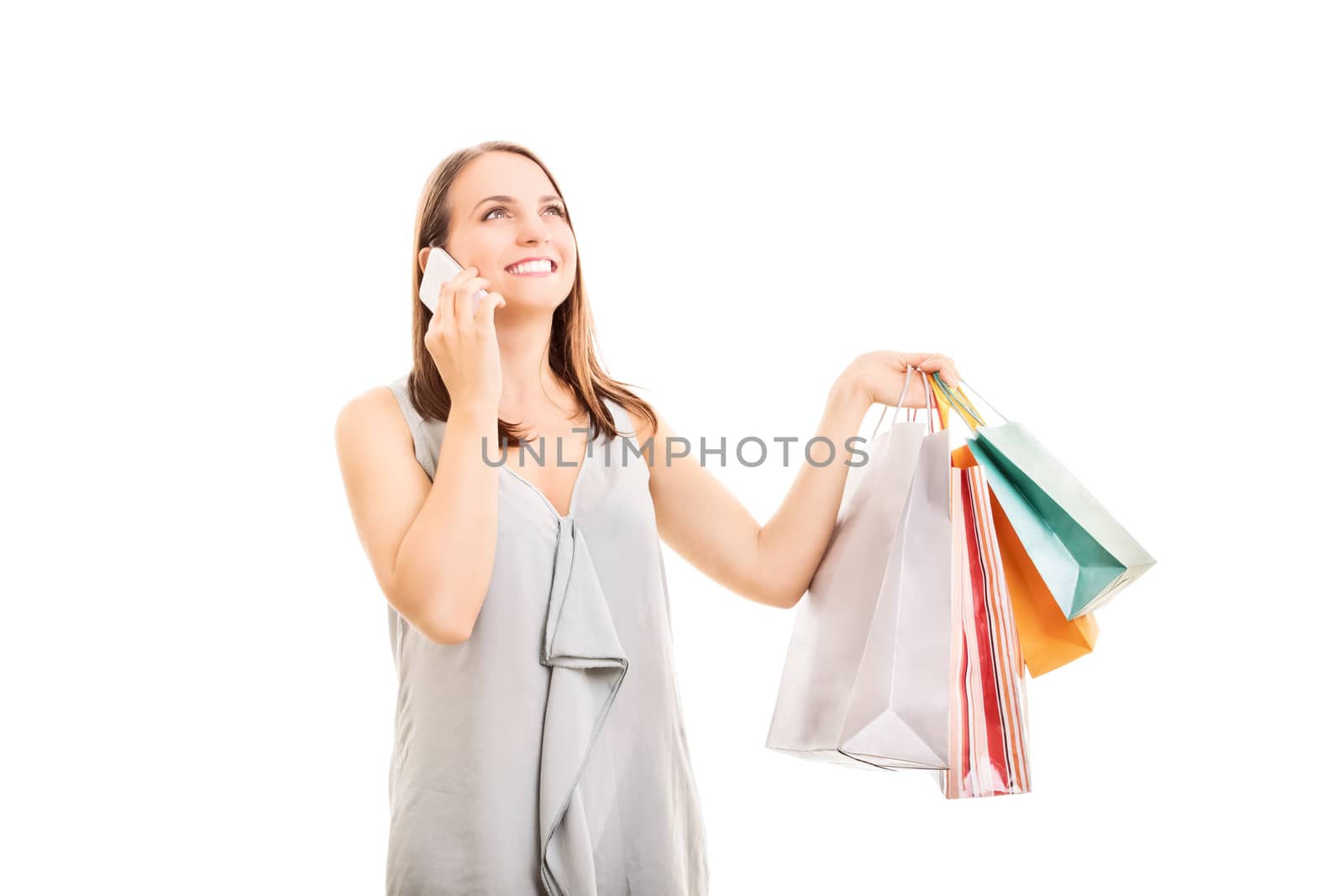 Beautiful smiling young girl holding shopping bags and talking on the mobile phone, isolated on white background.