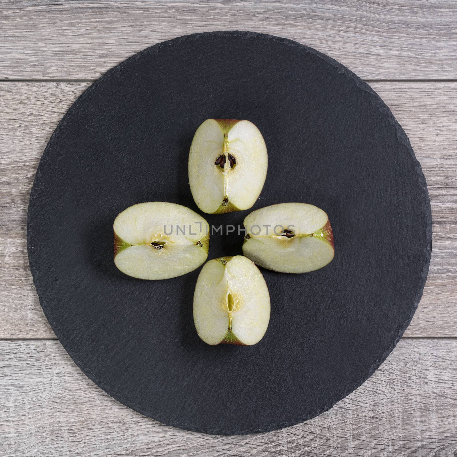 an apple cut into four wedges on a black plate