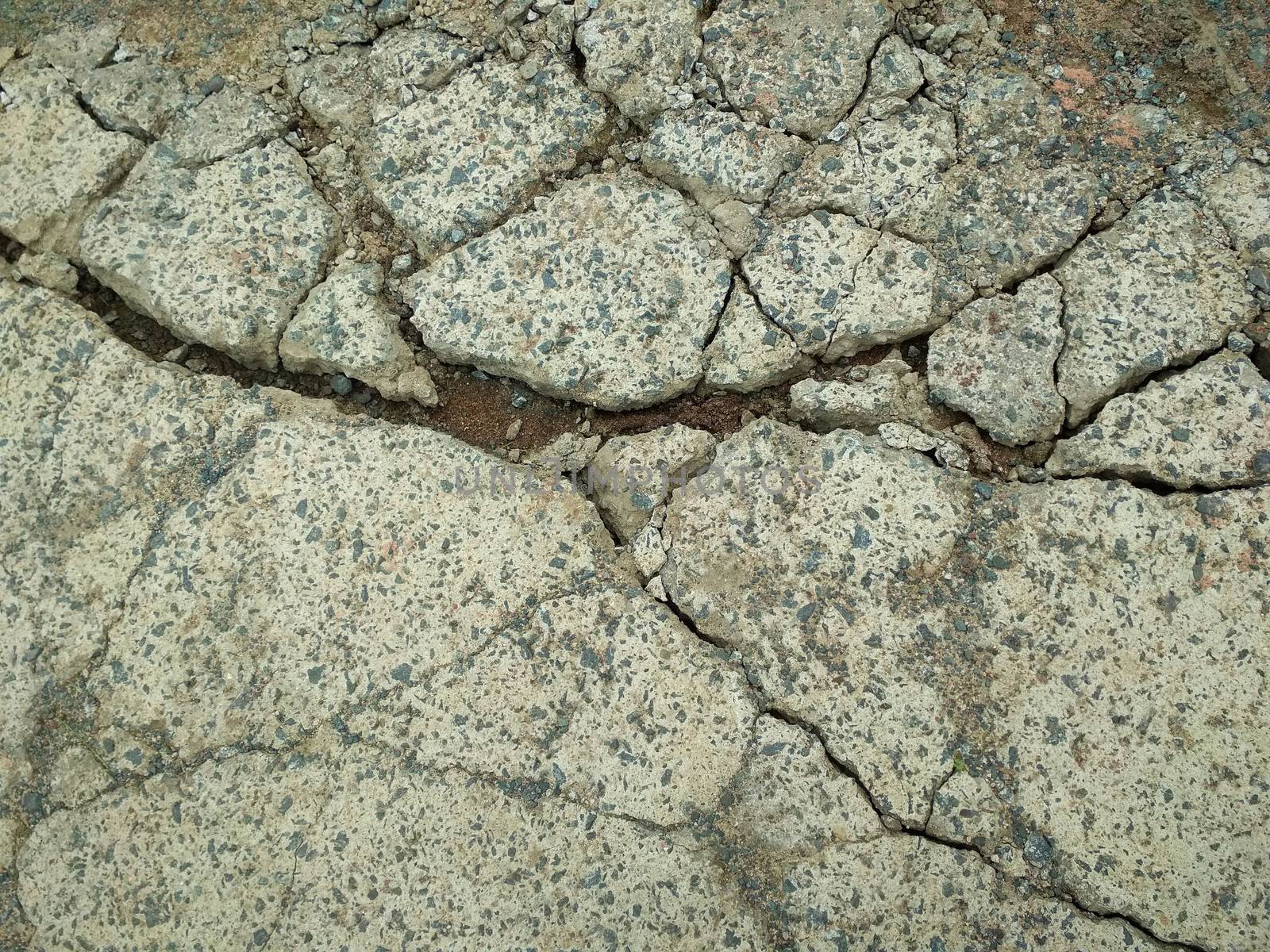 Deep dark fissures in road from concrete of a brighter color of.