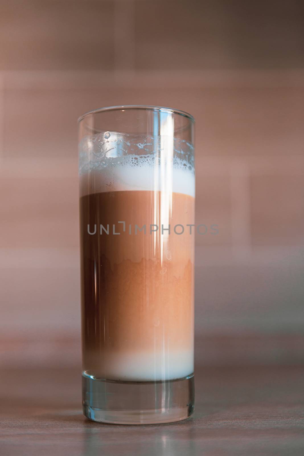 cup of multilayer coffee in a glass cup on brick background and stone table
