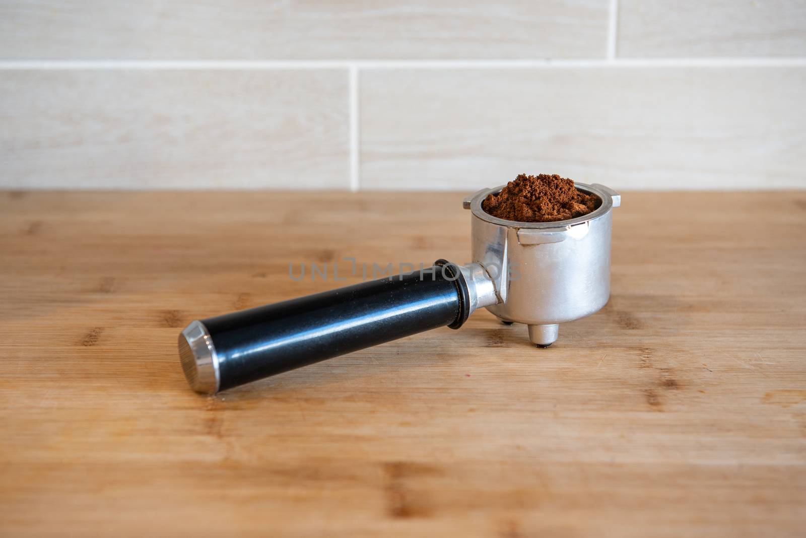 Filter holder with ground coffee on wooden table.