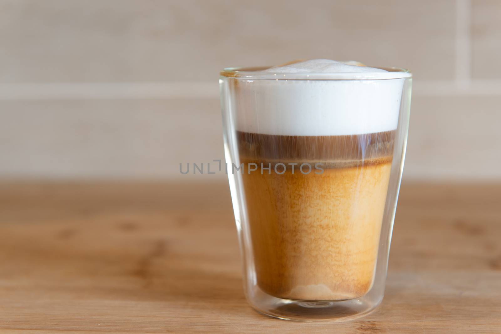 multilayer coffee or cappuccino in a glass cup on wooden table.