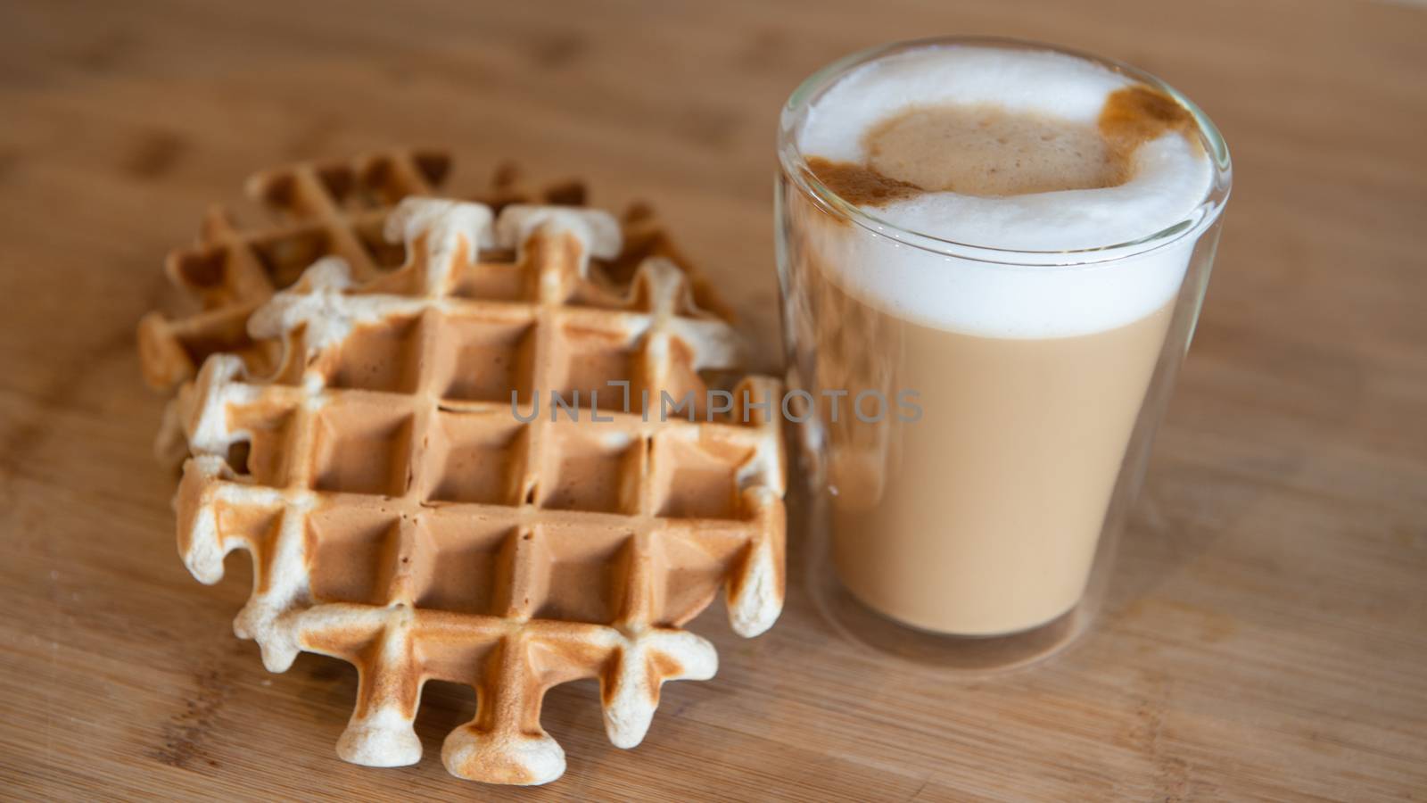 Glass cup of multilayer coffee with mini stroopwafel, syrupwaffles by marynkin