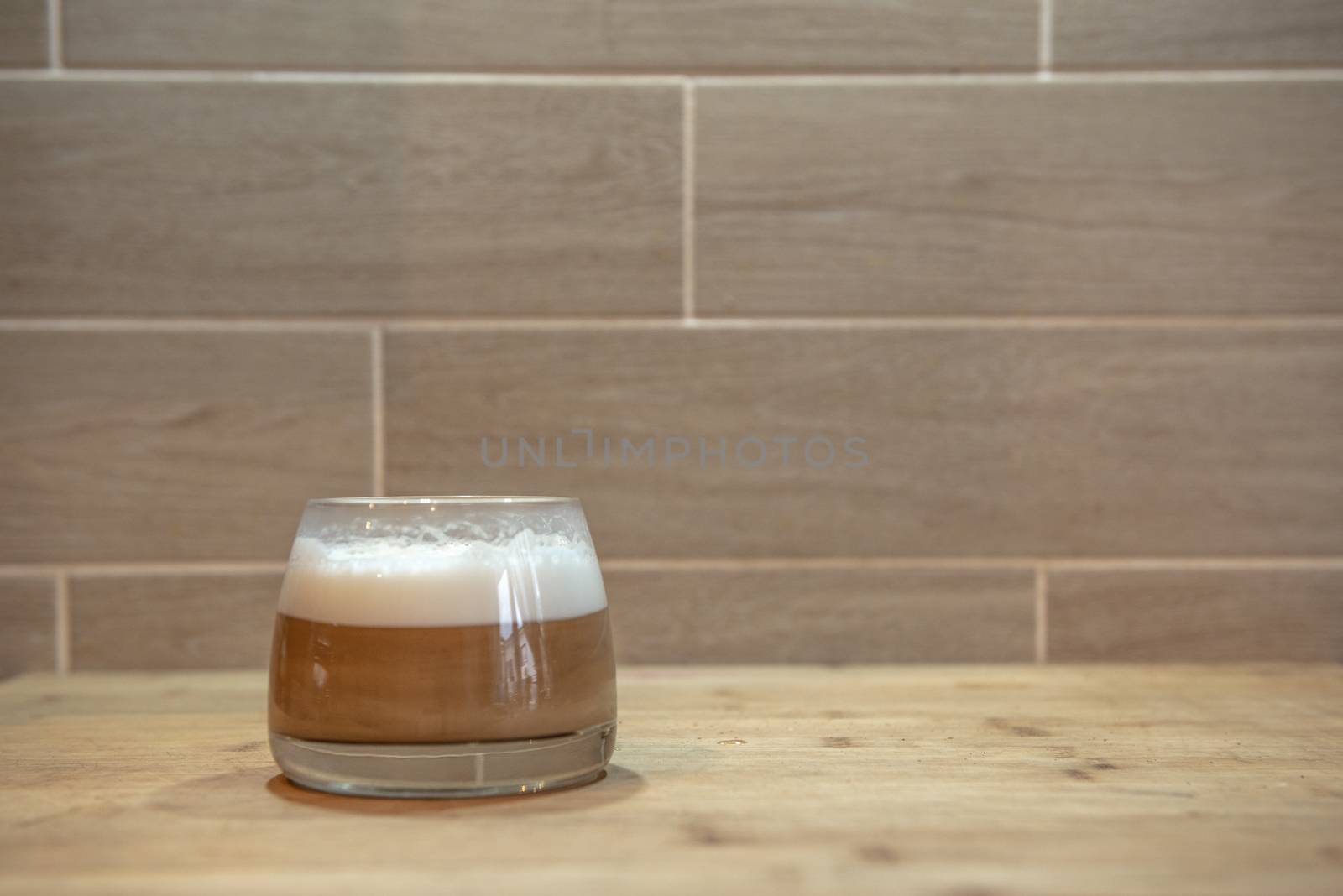 multilayer coffee or cappuccino in a glass cup on wooden table.