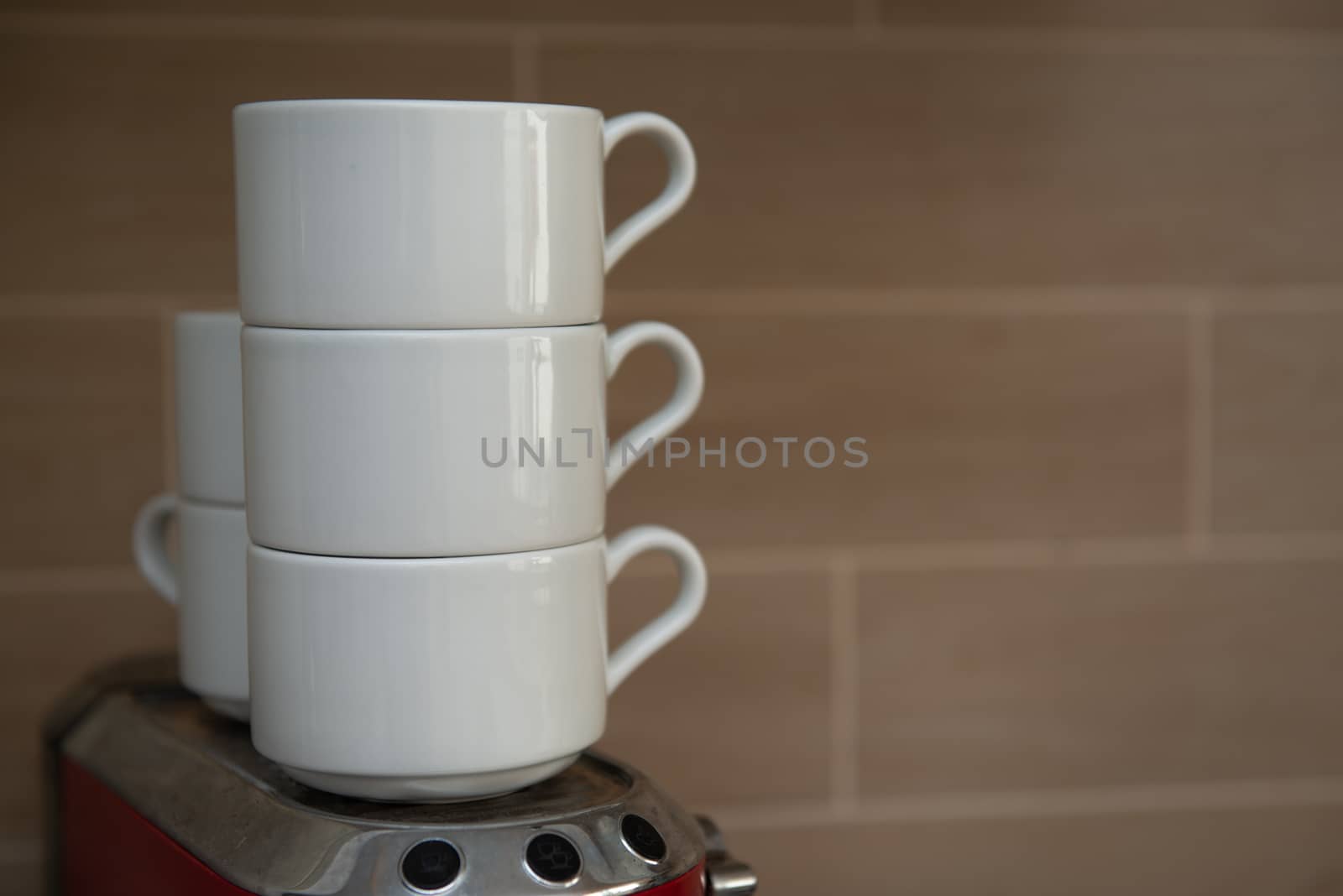 White coffee cups stand on top of each other against a gray wall.