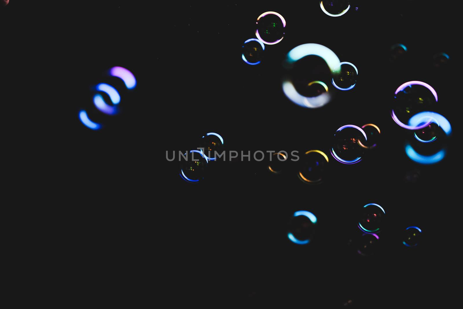 Colorful soap bubbles flying over darck background, shallow depth of field