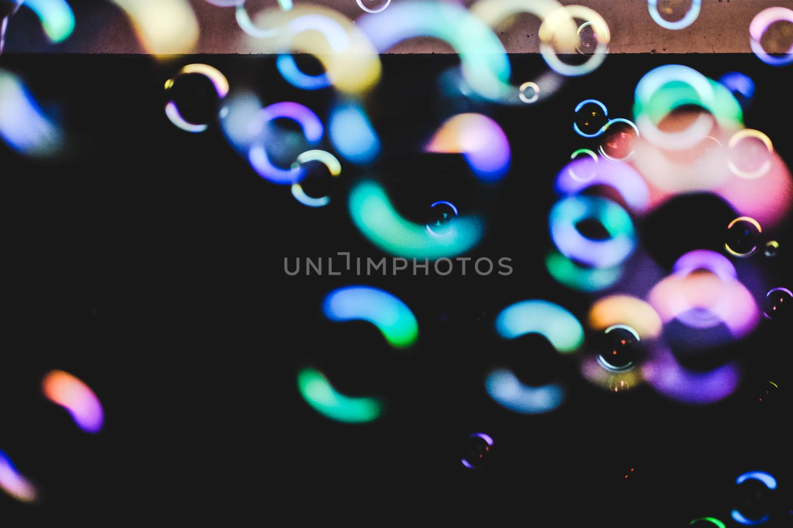 Colorful soap bubbles flying over darck background, shallow depth of field