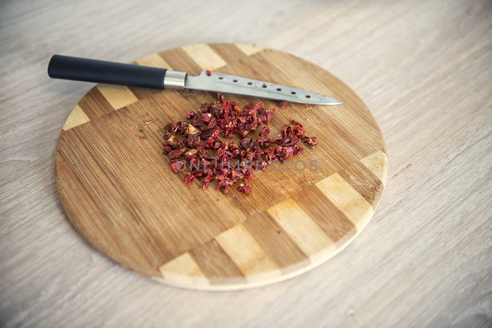 Dry tomatoes finely chopped on a cutting board by marynkin