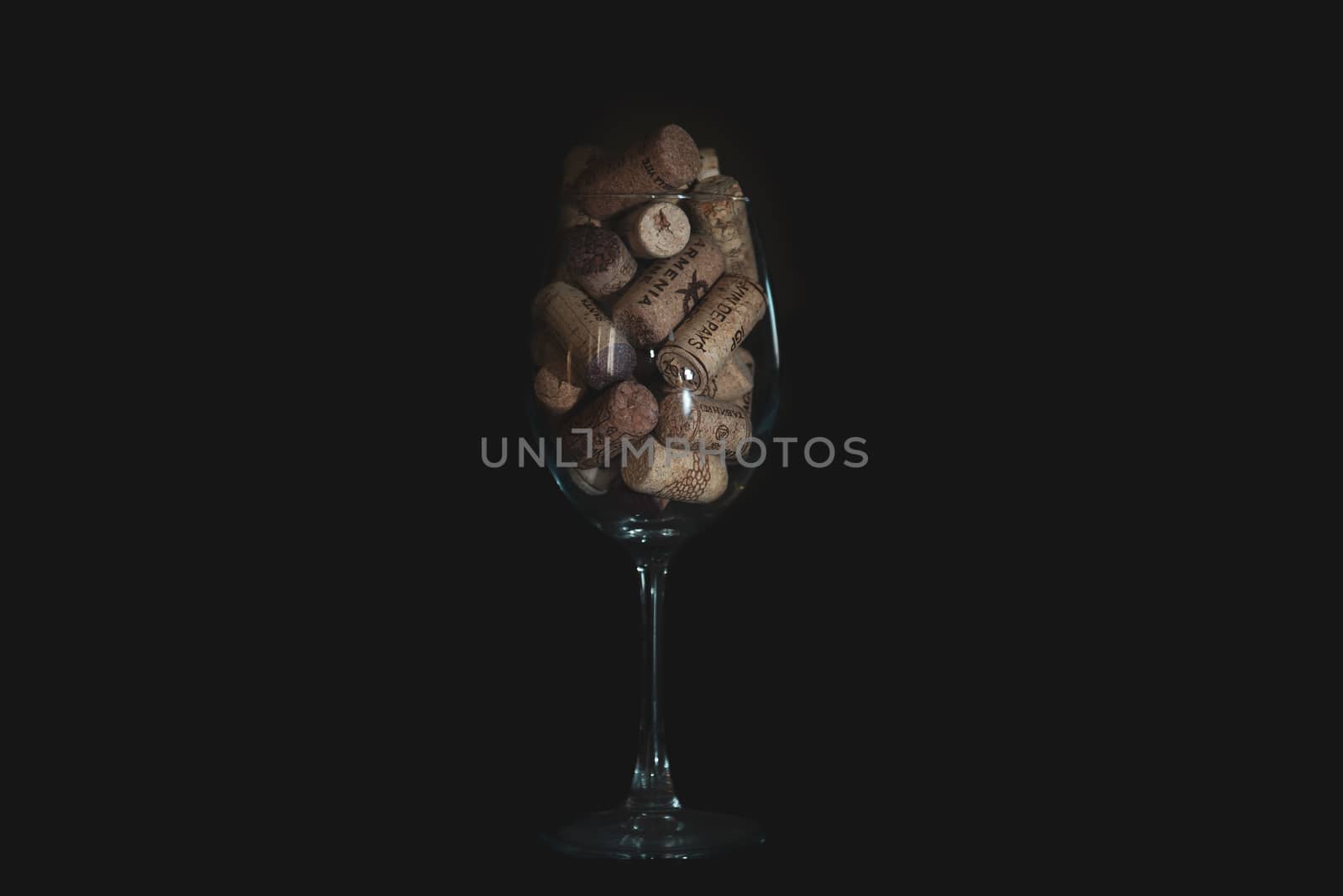 Heap of assorted wine corks in wine glass on black background