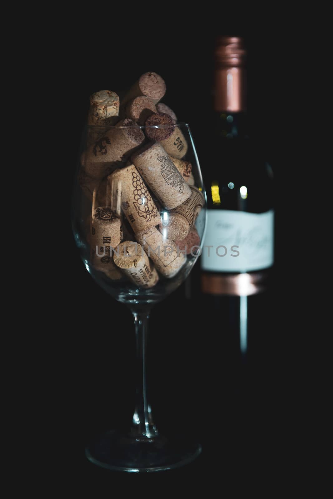 Heap of assorted wine corks in wine glass on black background