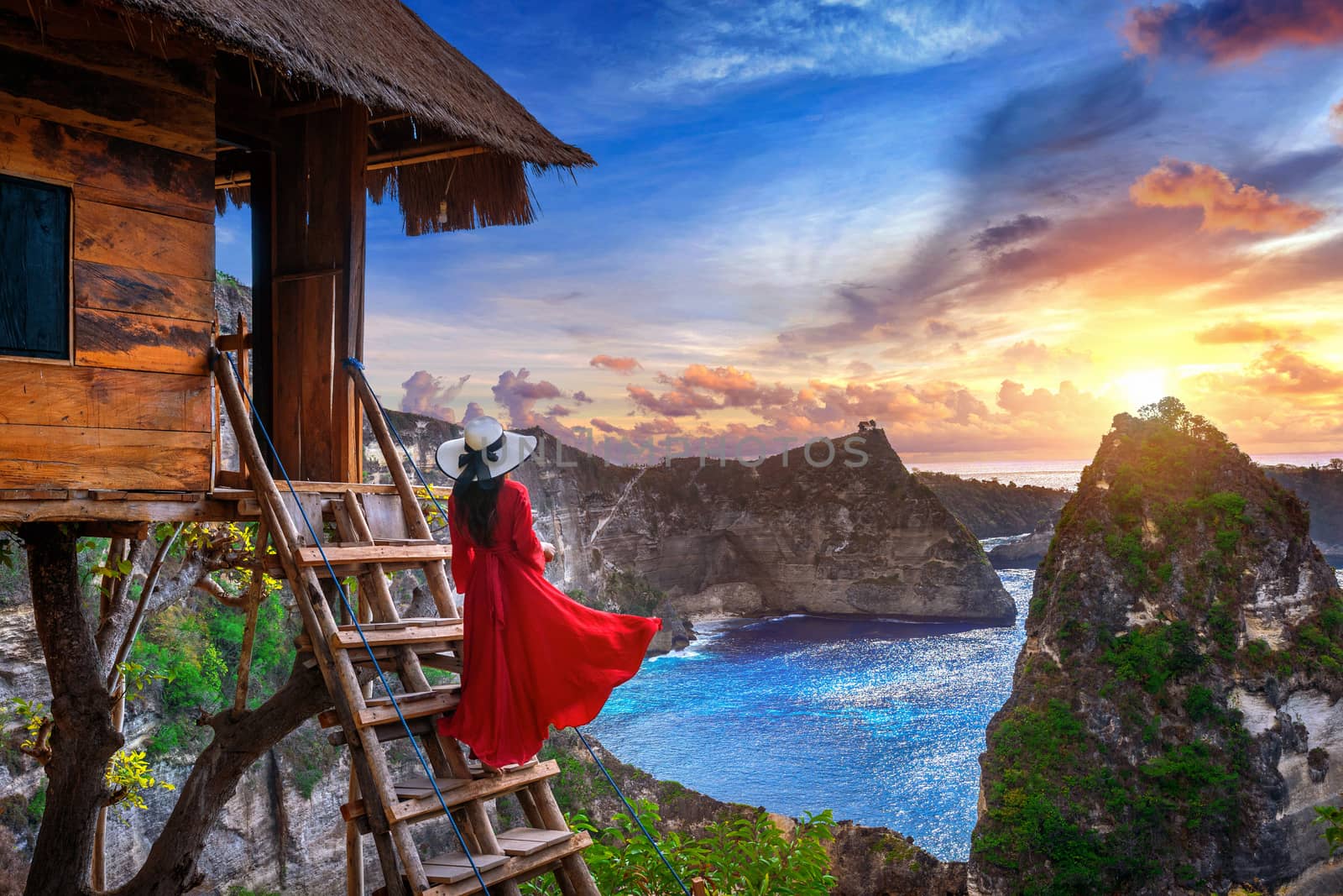 Young girl on steps of house on tree at sunrise in Nusa Penida island, Bali in Indonesia.