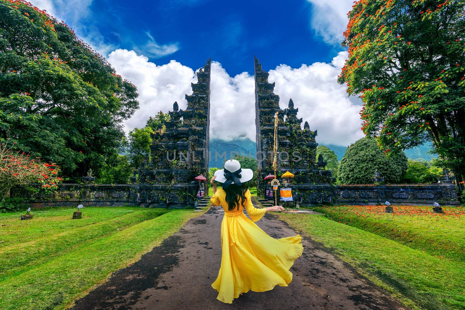 Woman walking at big entrance gate, Bali in Indonesia. by gutarphotoghaphy