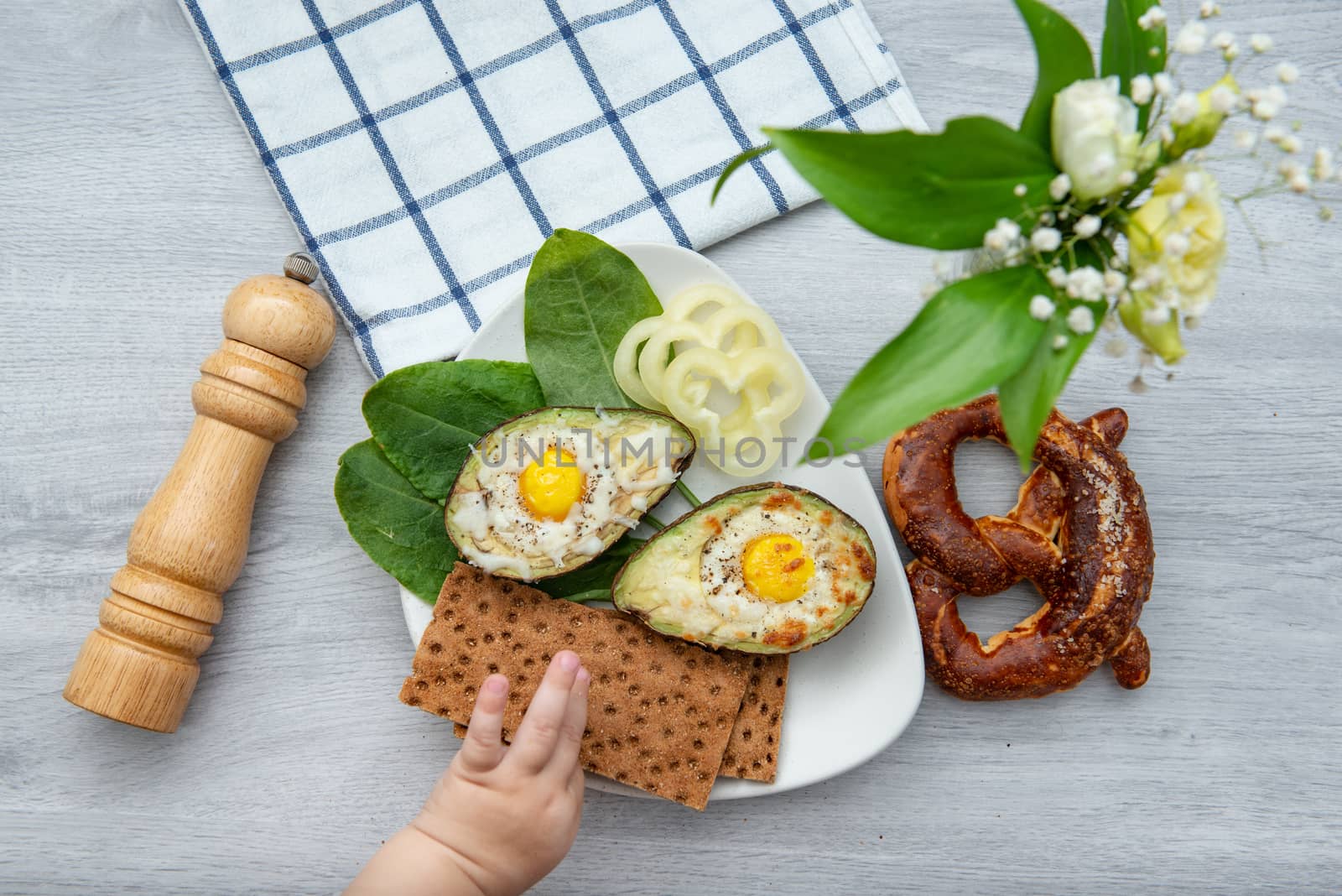 Eggs baked in avocado on plate with onion, juicy and pretzel