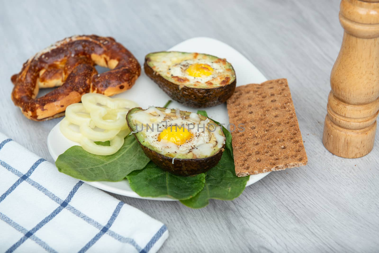 Eggs baked in avocado on plate. Wooden table
