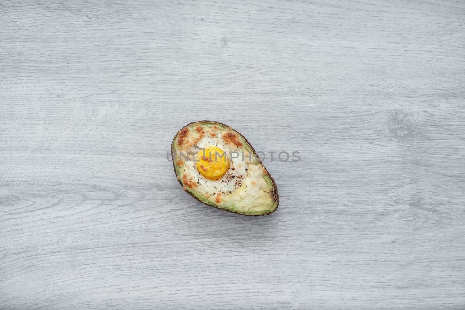 One egg baked in avocado on wooden table by marynkin