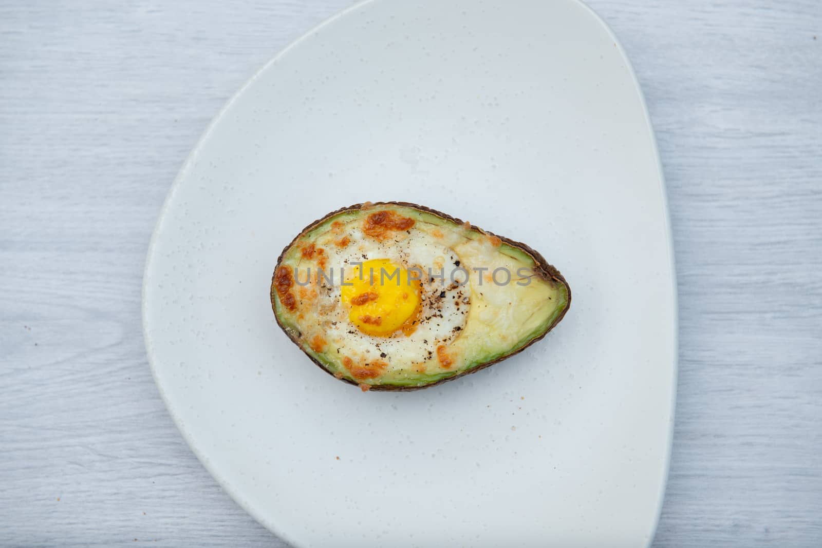 one egg baked in avocado on wooden table.