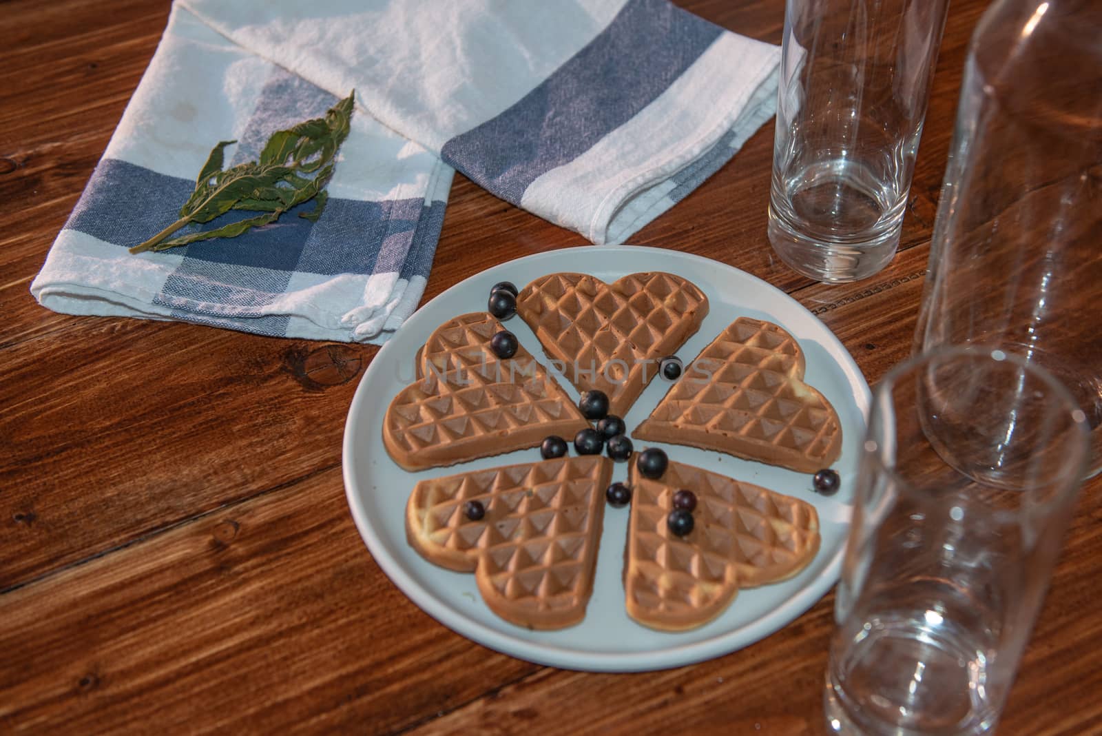 an empty bottle, two glasses and wafers on a plate. Wooden background