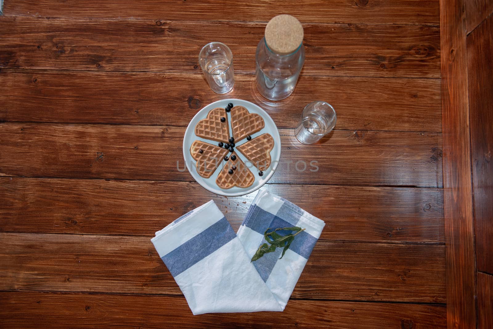 an empty bottle, two glasses and wafers on a plate. Wooden background