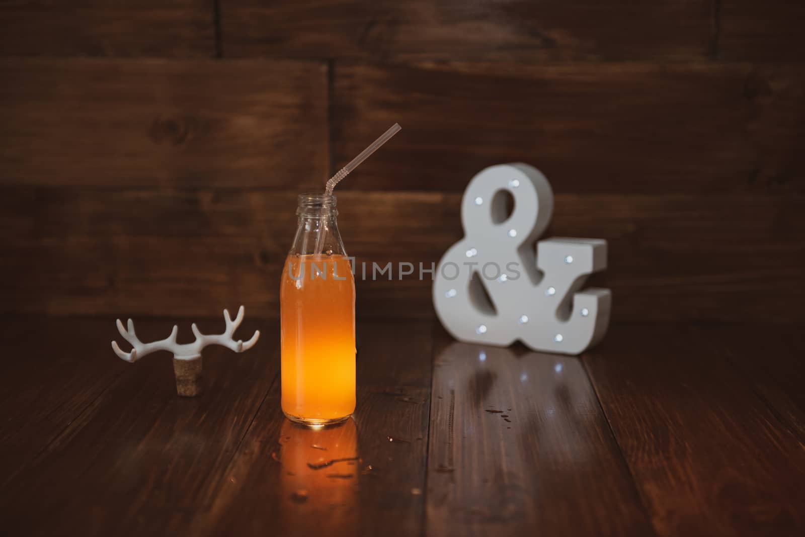 a vintage bottle of freshly squeezed juice on a wooden background and a glowing ampersand. by marynkin