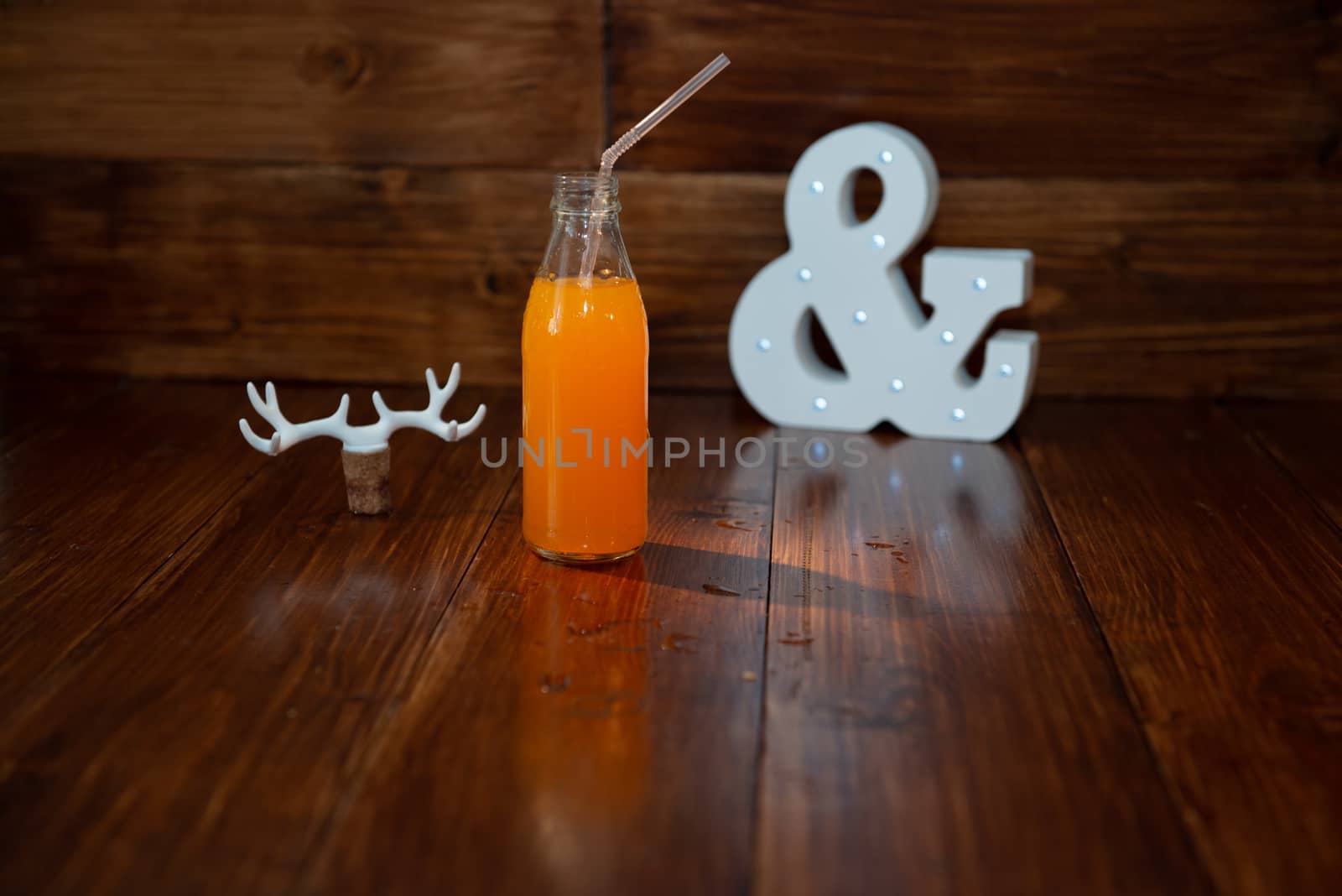 a vintage bottle of freshly squeezed juice on a wooden background and a glowing ampersand. Near wine cork decorated with deer antlers by marynkin