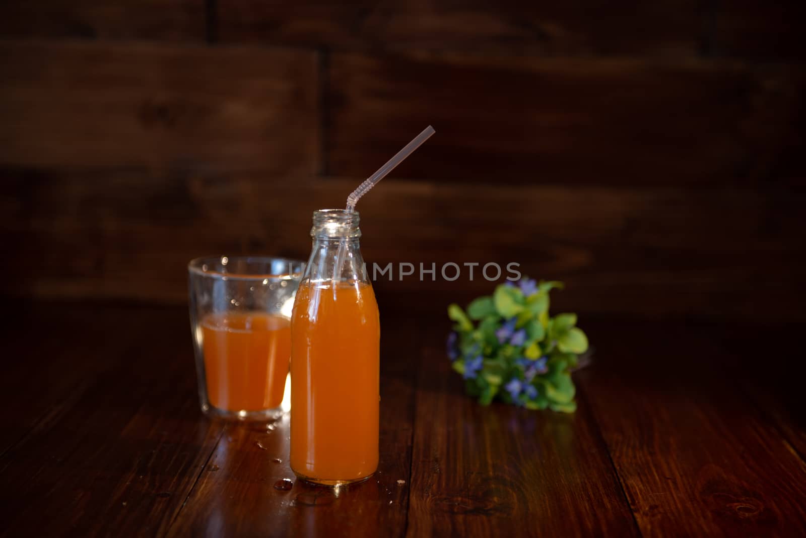 vintage bottle with juice, straw and flowers on wooden table by marynkin