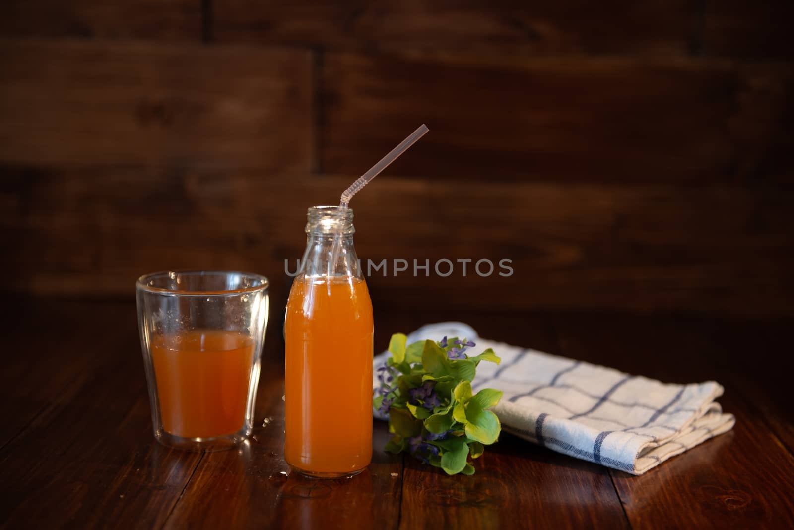 vintage bottle with juice, straw, flowers and towel on wooden table.