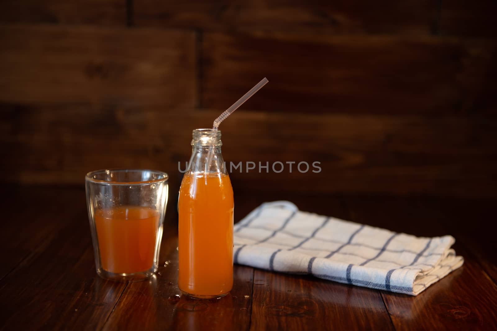 vintage bottle with juice, straw, and towel on wooden table.