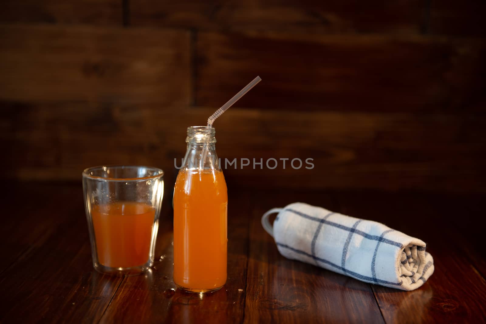 vintage bottle with juice, straw and towel on wooden table by marynkin