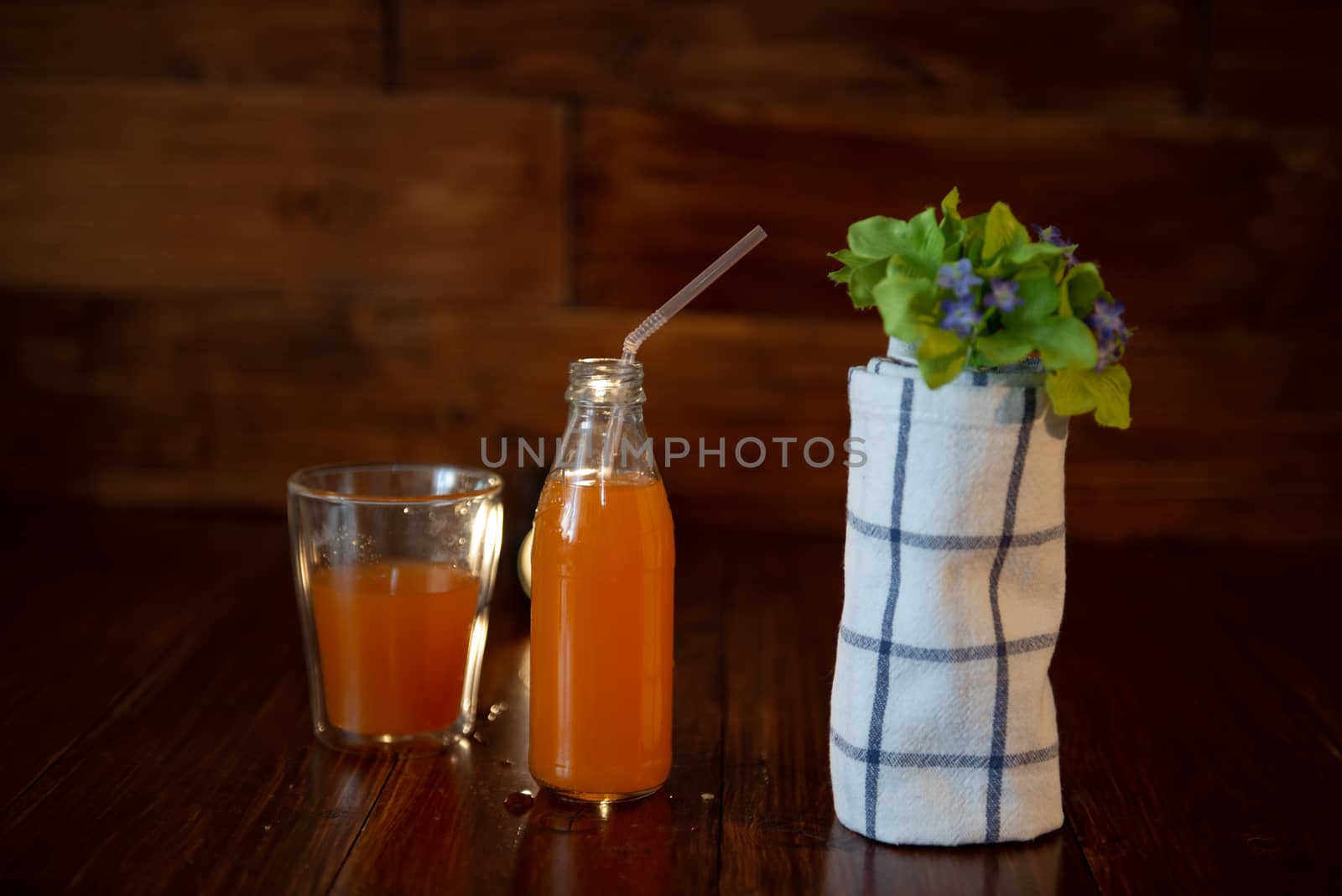 vintage bottle with juice, straw, flowers and towel on wooden table.