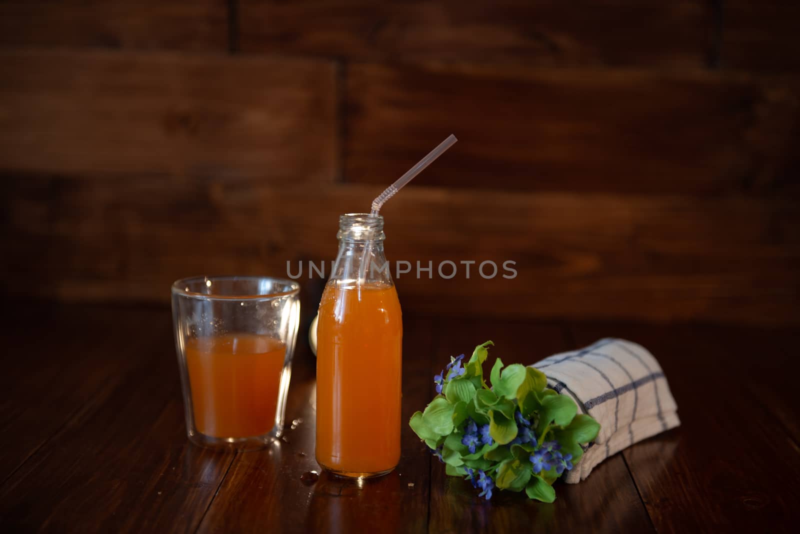 vintage bottle with juice, straw, flowers and towel on wooden table by marynkin