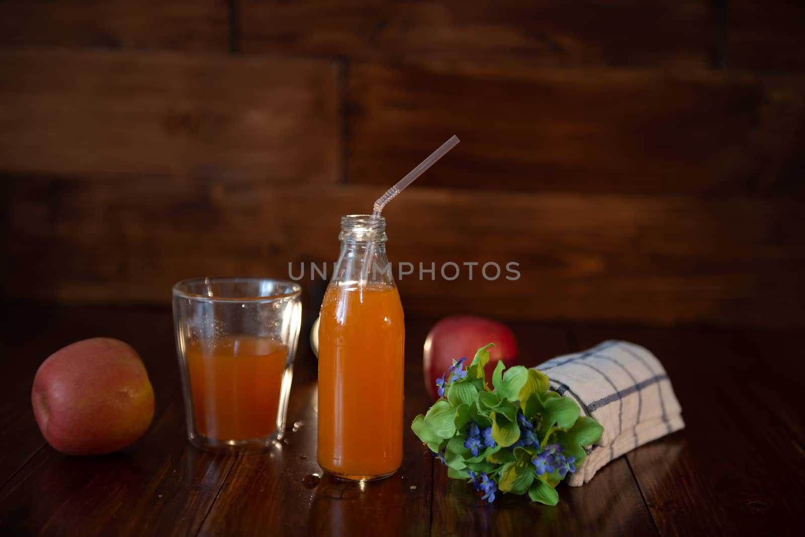 vintage bottle with juice, straw, flowers and towel on wooden table by marynkin