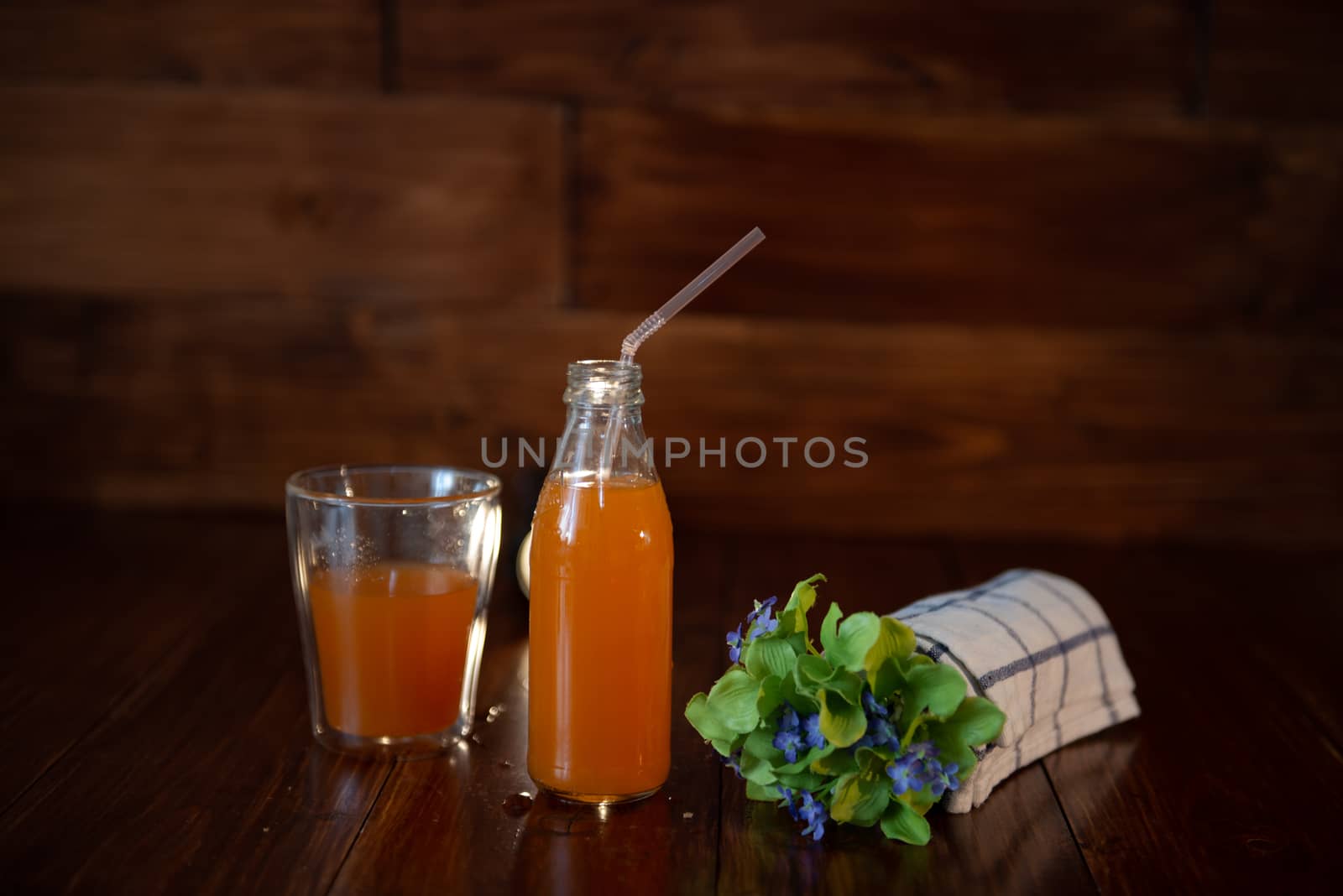 vintage bottle with juice, straw, flowers and towel on wooden table by marynkin
