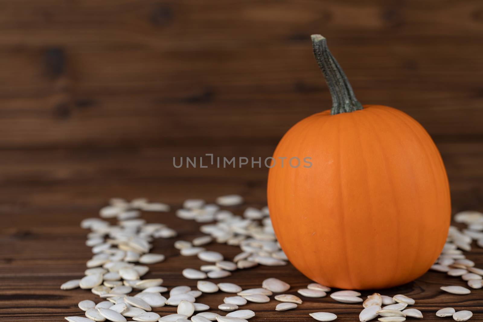 Fresh orange pumpkin and pimpkin seeds close-up on wooden background