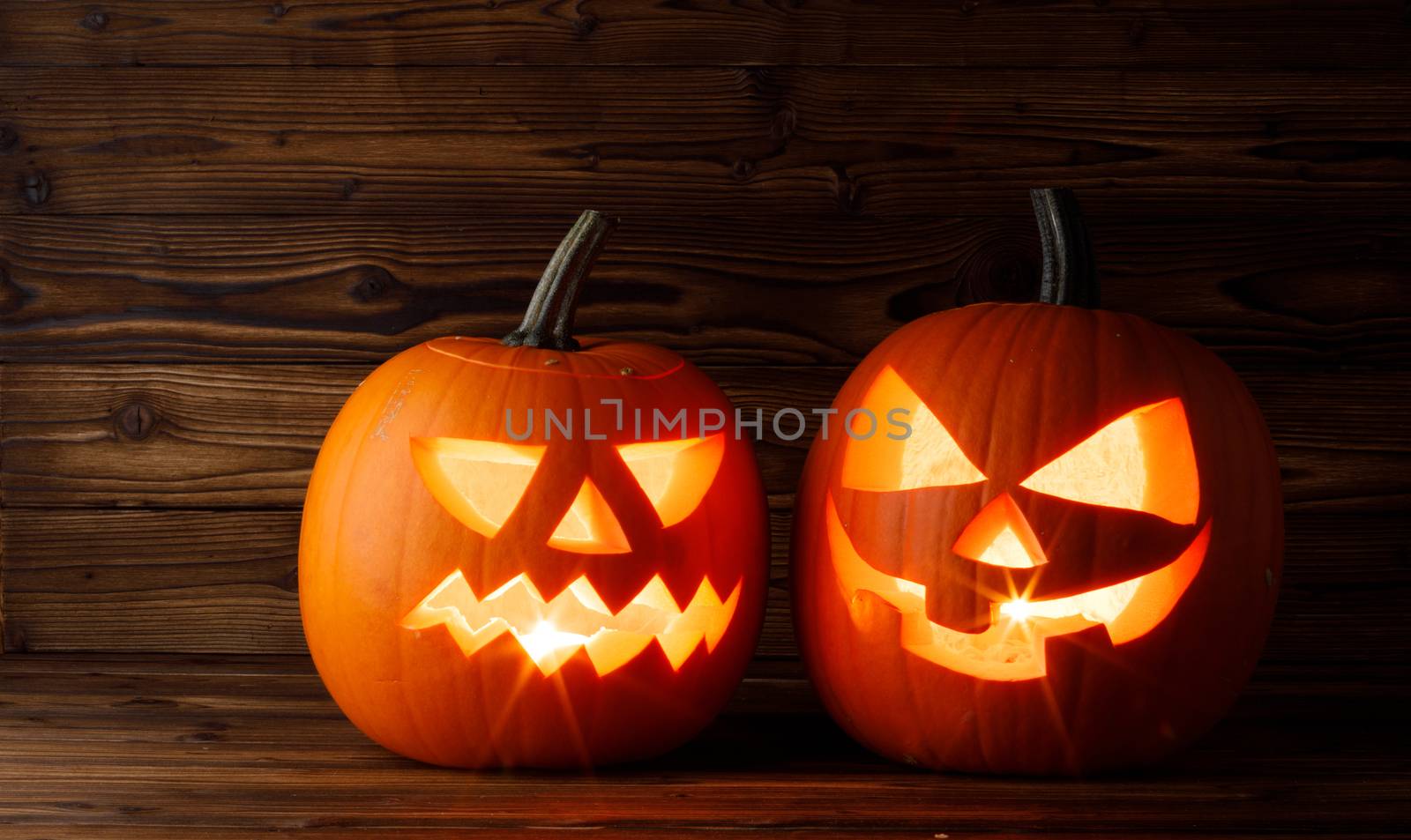 Halloween pumpkins head jack o lantern with candle inside on wooden background