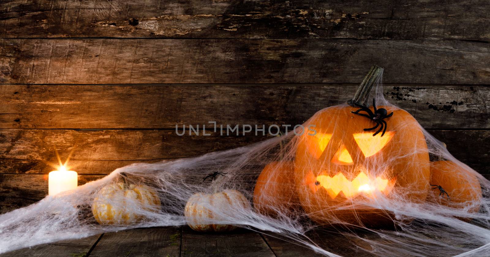 Jack O Lantern Halloween pumpkin, spiders on web and burning candles