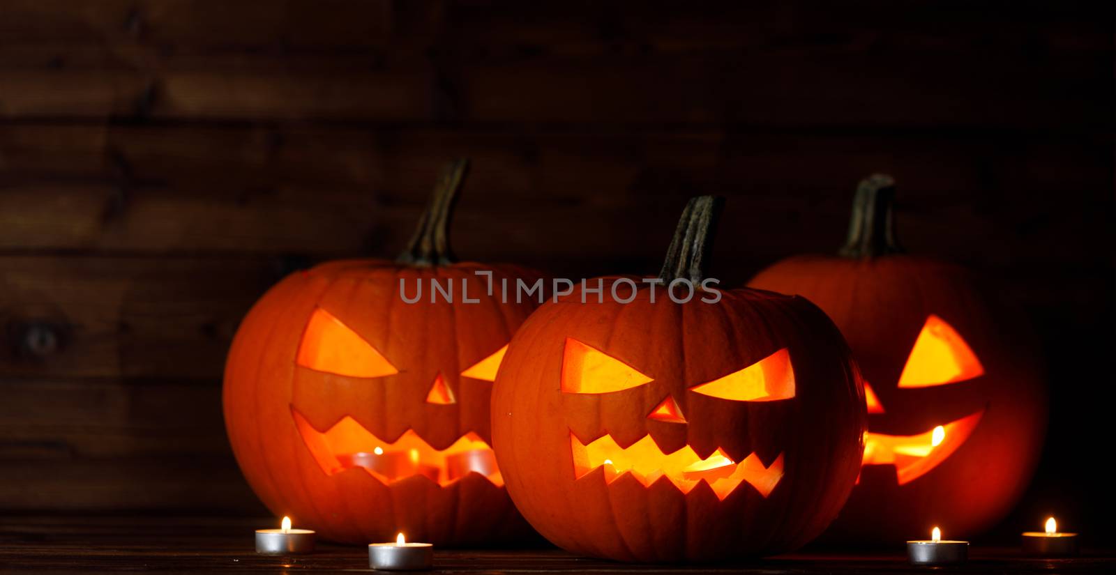 Group of Halloween pumpkin head jack o lantern and candles on dark wooden background