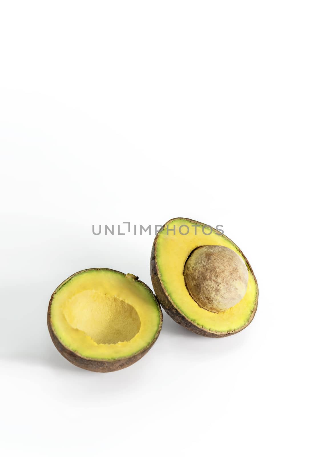 Whole and cut in half avocado fruit on white background