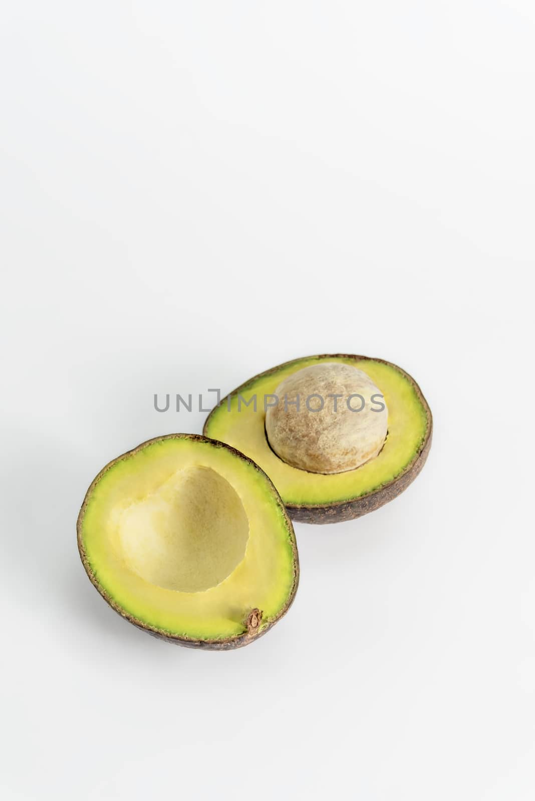 Whole and cut in half avocado fruit on white background