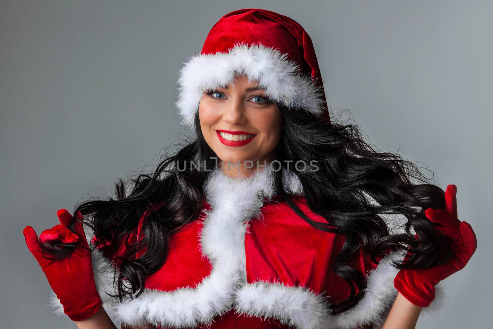 Christmas Woman in Santa Hat. Fashion Model with Makeup and Long Healthy Curly Hair