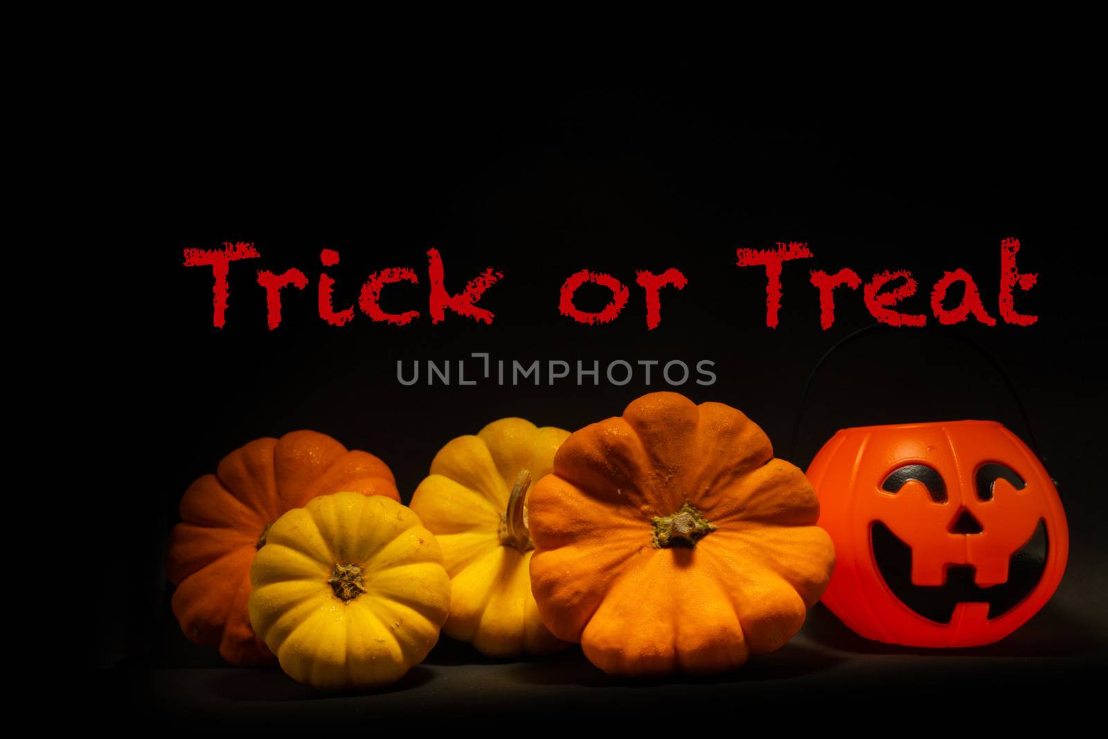 Halloween pumpkin on dark background with Trick or Treat text by peerapixs